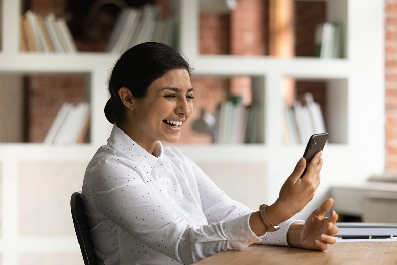 Happy woman read sms on cellphone enjoys good online news